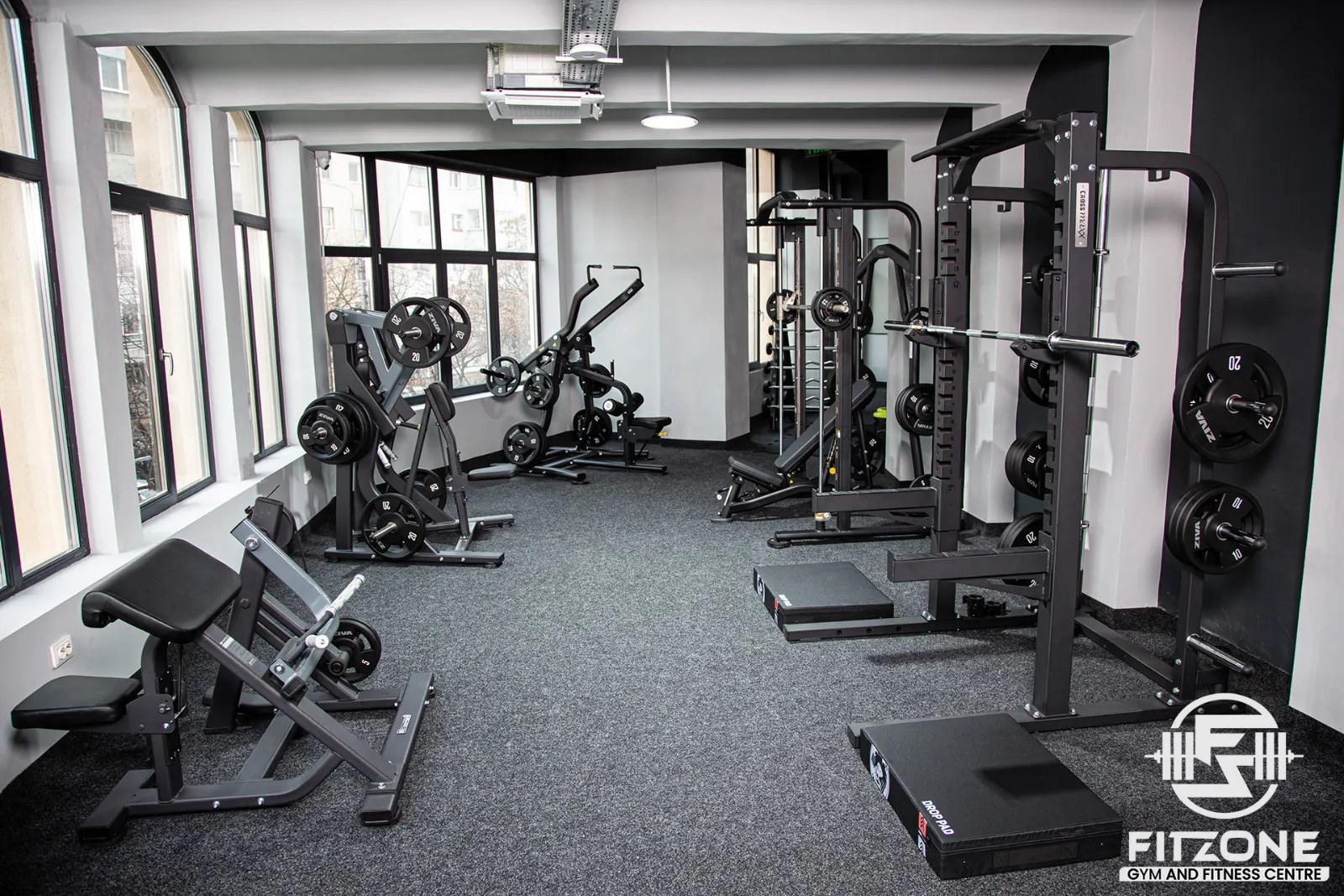 Zona de forță FitZone Ploiești, cu aparate și greutăți lângă ferestre.